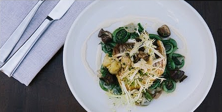 A plated spring dish at State Road — fish over fiddleheads with shaved cheese